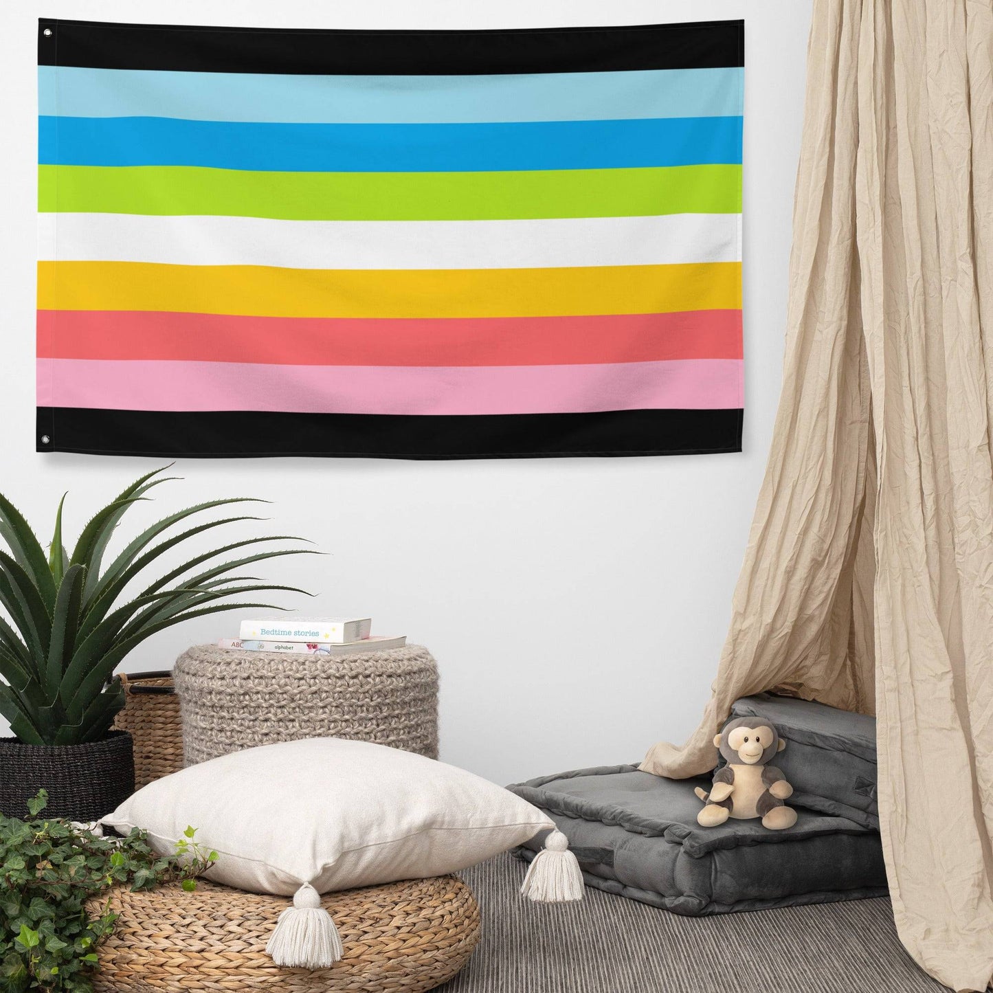 The Queer Pride Flag by Pridelity showcases vibrant horizontal stripes in blue, green, yellow, pink, and white, bordered by sleek black lines. This lively display from Rainbow Shop graces a white brick wall.