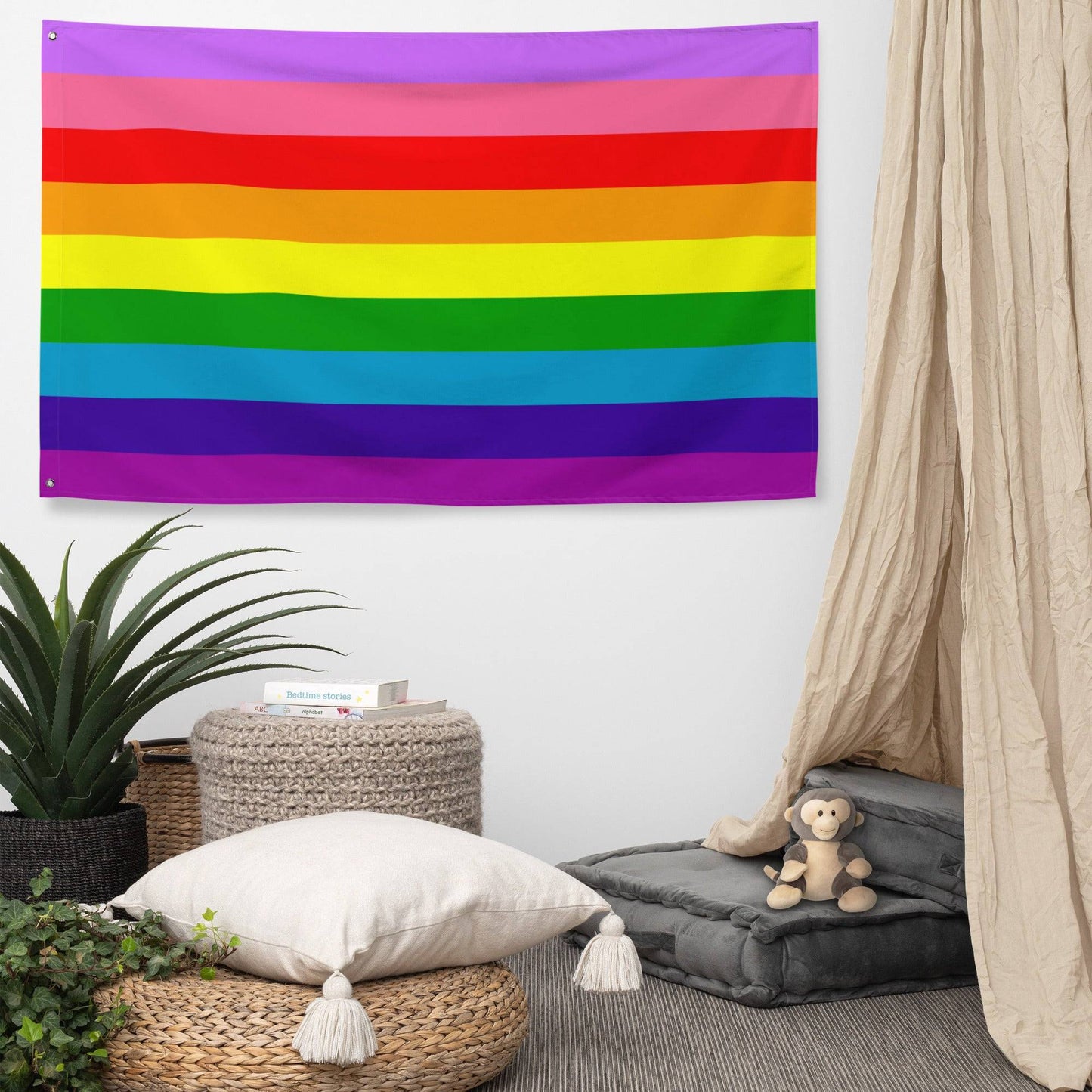 The Gilbert Baker Pride Flag from Pridelity, featuring vibrant horizontal stripes in red, orange, yellow, green, blue, and purple, elegantly adorns a white brick wall.