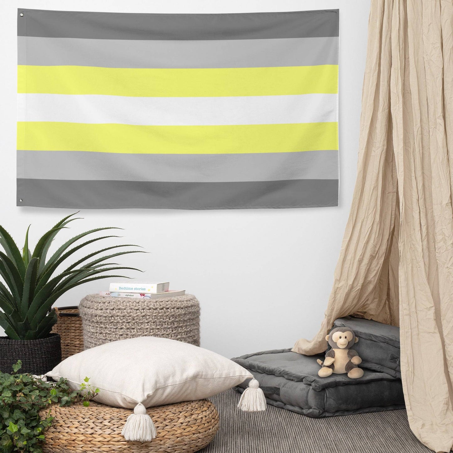 A Demigender Pride Flag from Pridelity, featuring horizontal stripes in gray, yellow, white, light yellow, and gray, adorns the textured white brick wall backdrop of a rainbow shop.
