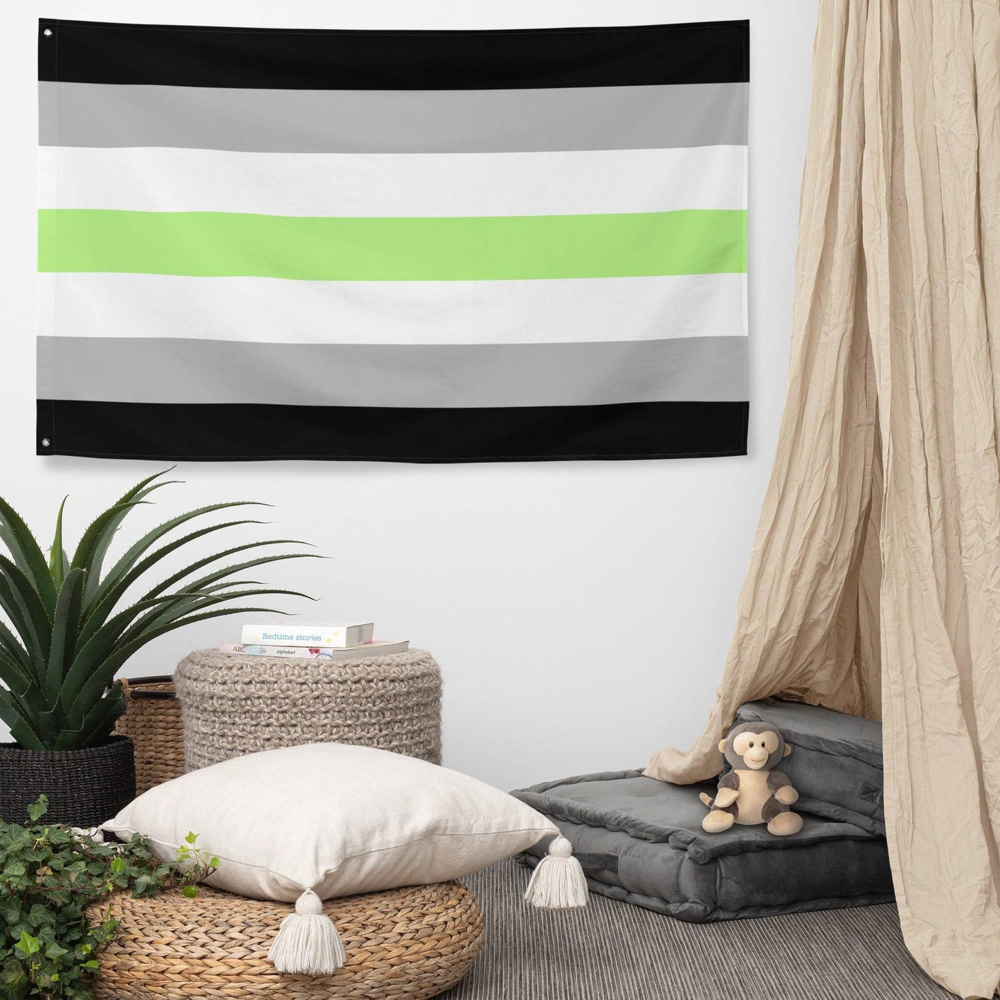The Agender Pride Flag by Pridelity, showcasing horizontal stripes in black, gray, white, a central green stripe, followed by white, gray, and black once more, is prominently displayed as part of our Pride Collections against a white brick wall.