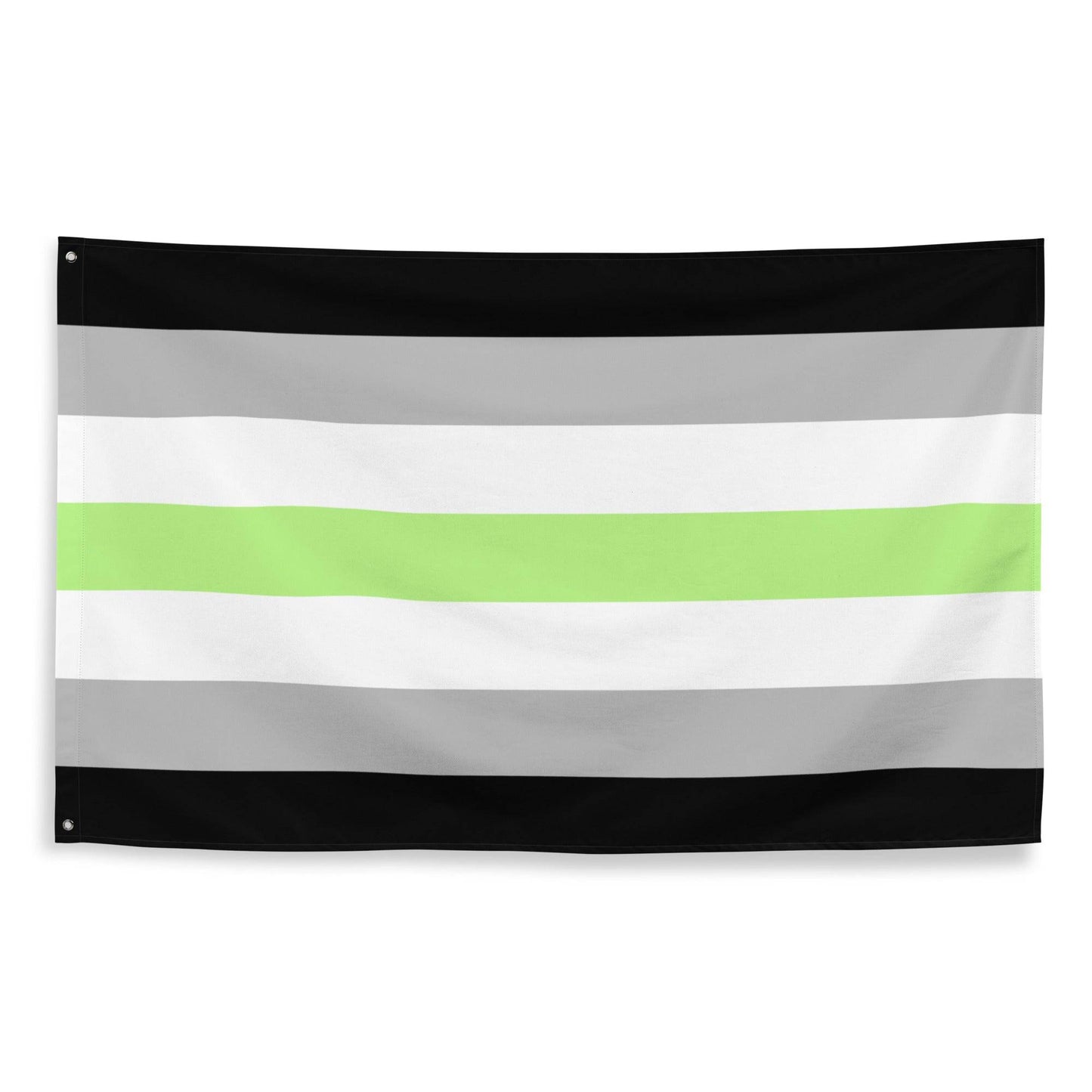 The Agender Pride Flag by Pridelity, showcasing horizontal stripes in black, gray, white, a central green stripe, followed by white, gray, and black once more, is prominently displayed as part of our Pride Collections against a white brick wall.