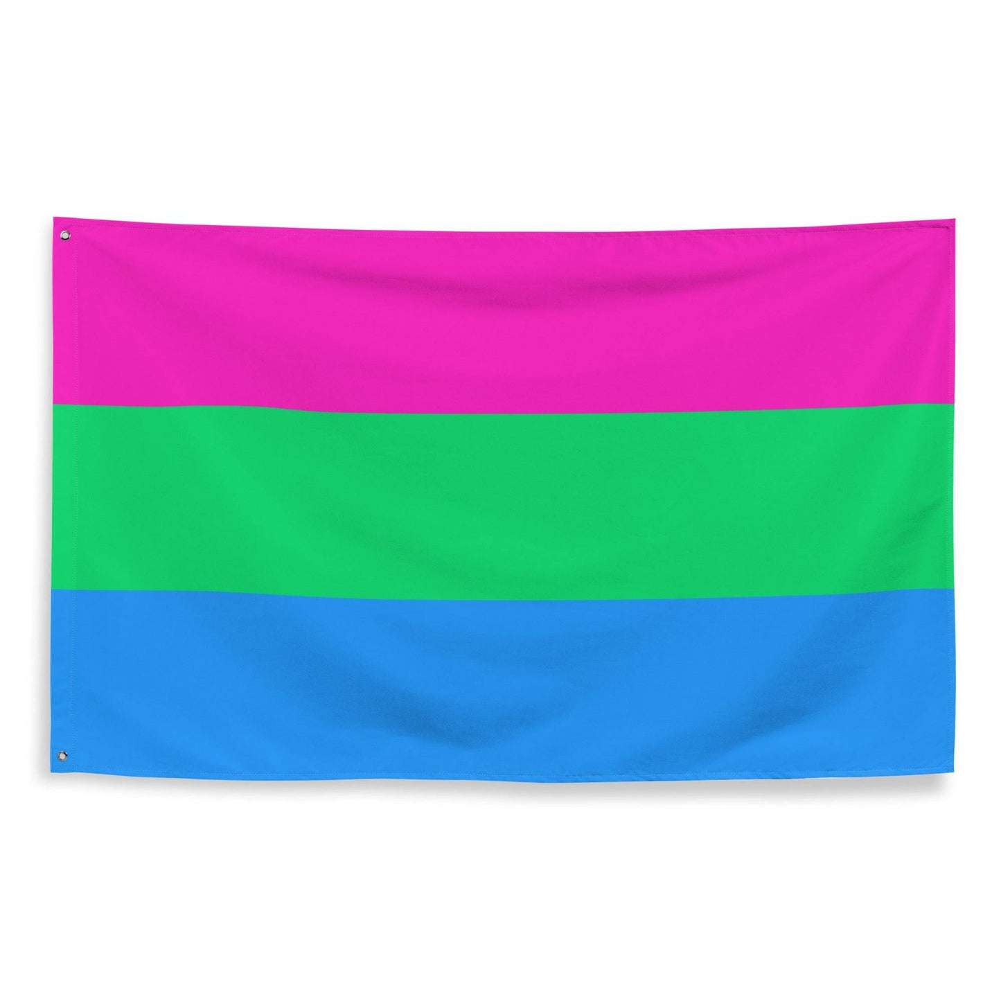 A vibrant Polysexual Flag, featuring three horizontal stripes with pink on top, green in the middle, and blue at the bottom, hangs elegantly on a white brick wall. From Pridelity, it adds a splash of color reminiscent of a rainbow shop display.