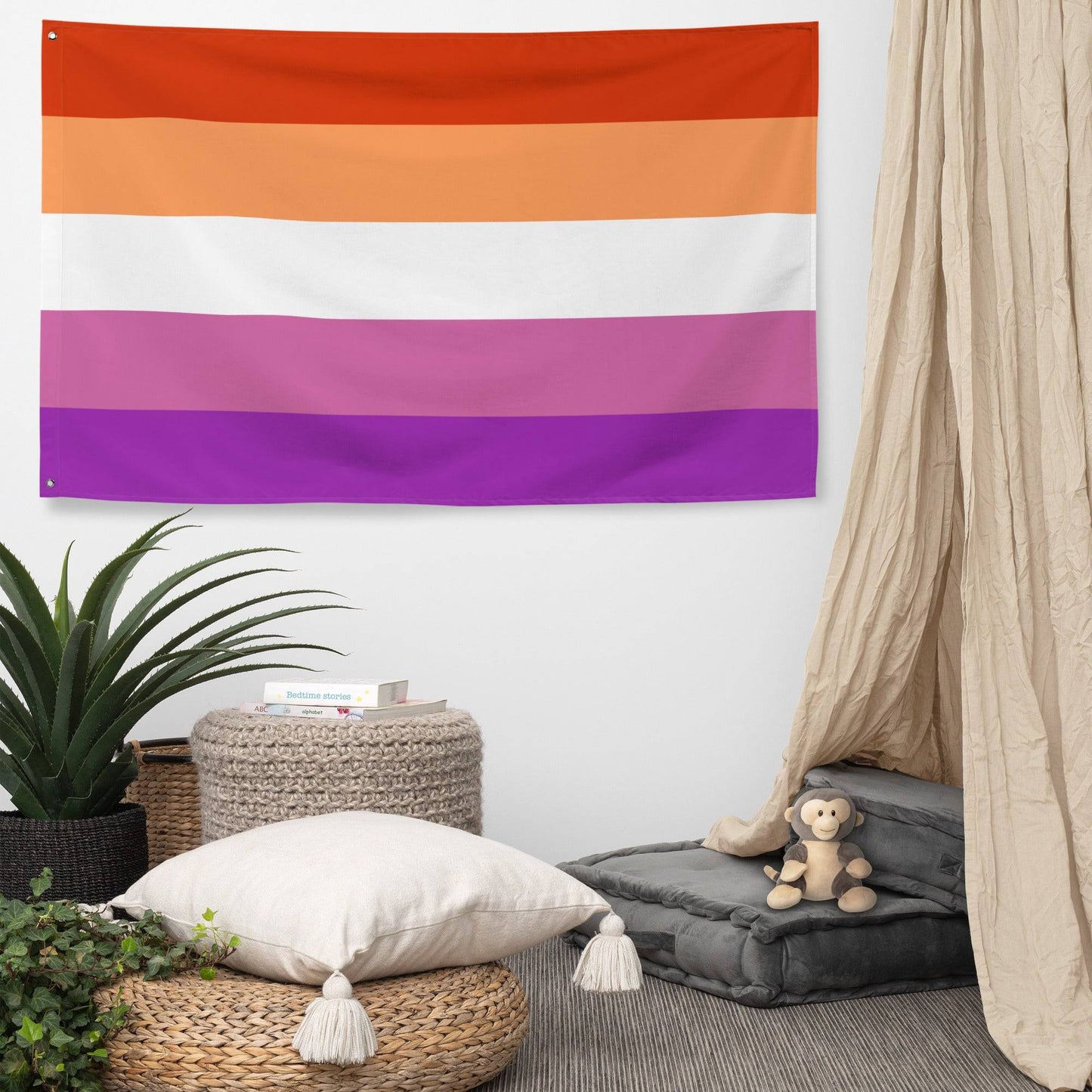 A Pridelity Lesbian Pride Flag with horizontal stripes in dark orange, orange, light orange, white, pink, and purple hung on a white brick wall outside the Rainbow Shop.