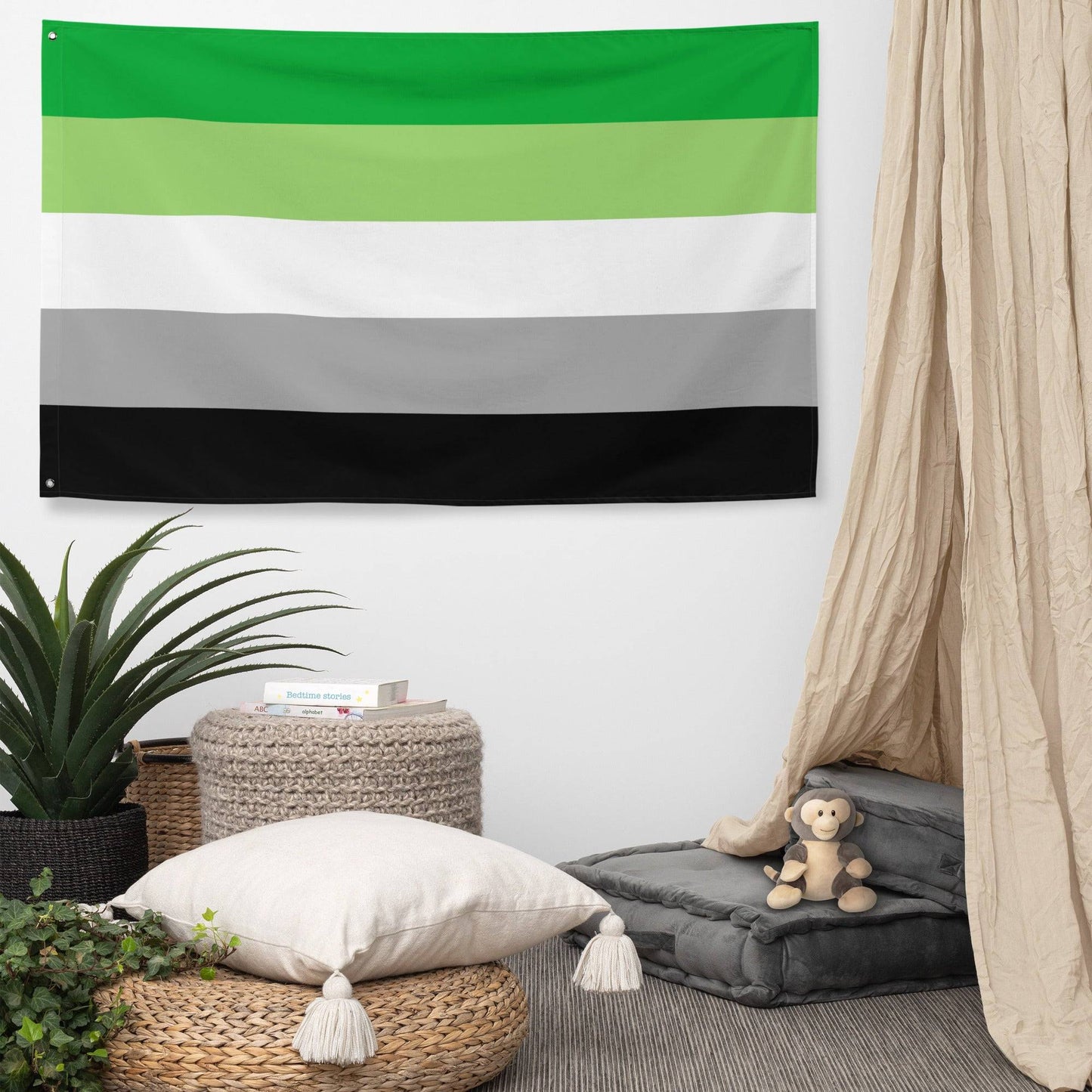 Image of Pridelity’s Aromantic Pride Flag hanging on a white brick wall, showcasing the vibrant colors of dark green, light green, white, gray, and black. This striking piece is part of our exclusive Pride Collections.