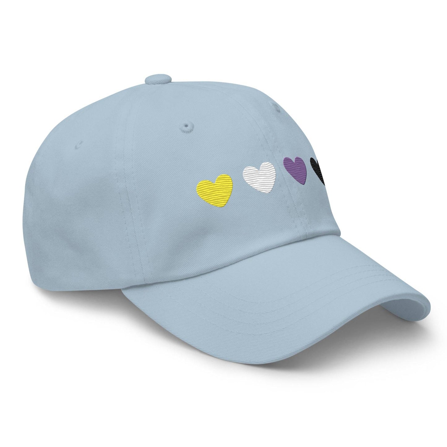 The "Nonbinary Hearts Cap" by Pridelity, in a stone color, features four heart symbols embroidered on the front in yellow, white, purple, and black, adding a subtle yet stylish touch to your pride outfits.