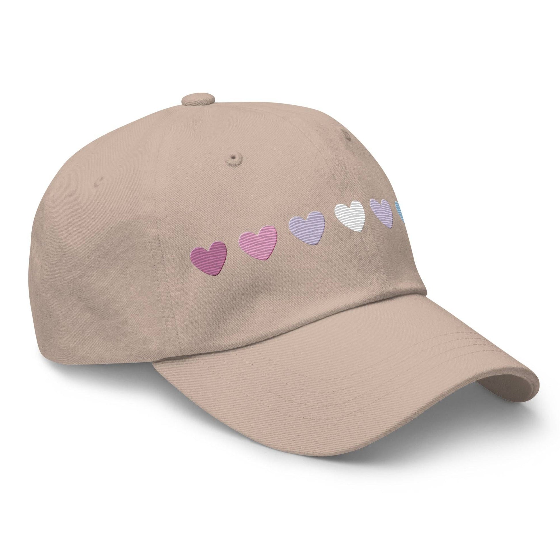 The Pridelity Bigender Hearts Cap, part of our Pride Collection, showcases a row of seven gradient heart symbols transitioning in color from pink to white to blue on a black base.