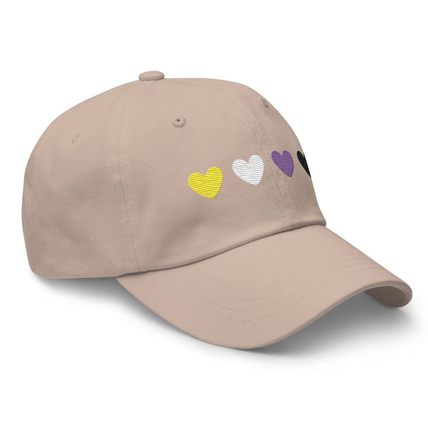 The "Nonbinary Hearts Cap" by Pridelity, in a stone color, features four heart symbols embroidered on the front in yellow, white, purple, and black, adding a subtle yet stylish touch to your pride outfits.