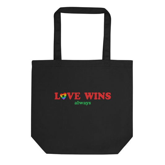 The Pridelity Love Wins, Always Tote Bag in black is available at the Rainbow Store. It showcases the words "LOVE WINS" in bold red letters, with a heart in vibrant rainbow colors replacing the letter "O," and the word "always" beautifully written in green beneath it. The tote bag includes two sturdy handles for convenient carrying.