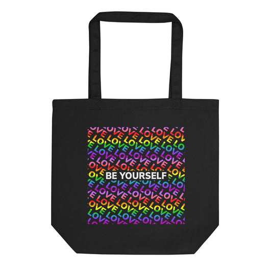 Introducing the "Be Yourself Tote Bag" from Pridelity: a stylish black tote adorned with a vibrant design on the front. Celebrate Pride with its backdrop of the word "LOVE" repeated in rainbow colors, complemented by "BE YOURSELF" boldly showcased in white. This unique piece is part of our exclusive Pride Merch collection.