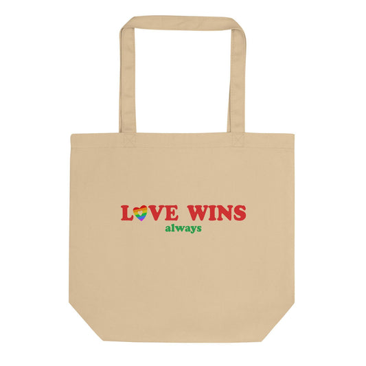 The Pridelity Love Wins, Always Tote Bag in black is available at the Rainbow Store. It showcases the words "LOVE WINS" in bold red letters, with a heart in vibrant rainbow colors replacing the letter "O," and the word "always" beautifully written in green beneath it. The tote bag includes two sturdy handles for convenient carrying.