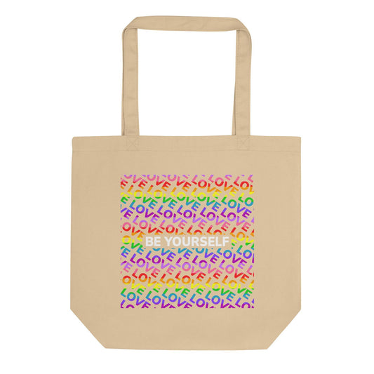 Introducing the "Be Yourself Tote Bag" from Pridelity: a stylish black tote adorned with a vibrant design on the front. Celebrate Pride with its backdrop of the word "LOVE" repeated in rainbow colors, complemented by "BE YOURSELF" boldly showcased in white. This unique piece is part of our exclusive Pride Merch collection.