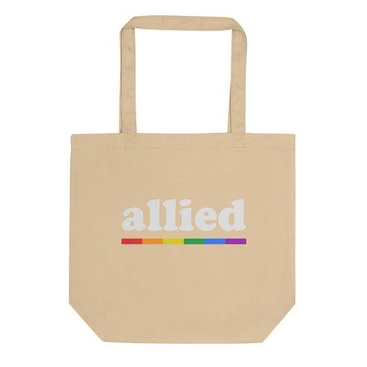The Pridelity "Allied Tote Bag" is a black tote with long handles, showcasing the word "allied" in white with a horizontal rainbow stripe beneath it, making it a stylish addition to any Pride Collection.