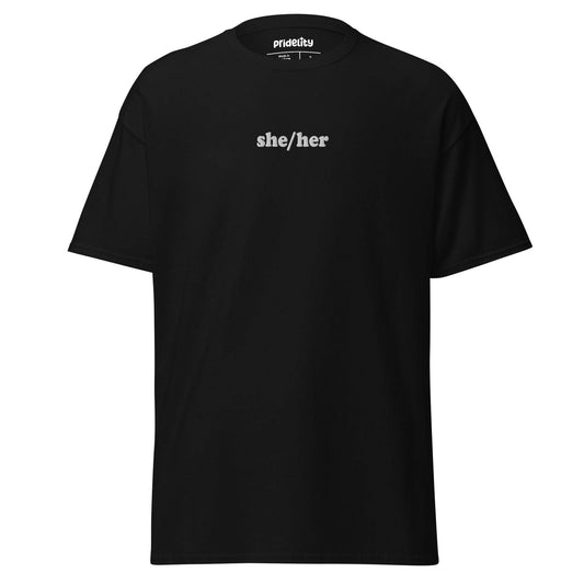 A black She/Her T-shirt by Pridelity showcases the words "she/her" in bold white text on the front, with the collar tag proudly reading "Prideify.