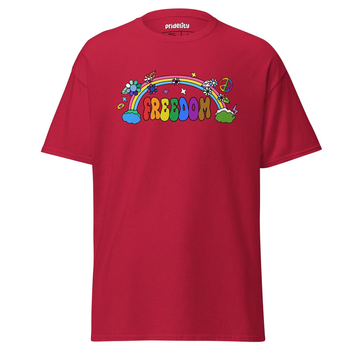 The Freedom T-Shirt by Pridelity features a colorful, cartoon-style design with "FREEDOM" in vibrant letters. A rainbow arches above clouds, flowers, and stars on the beige fabric, creating a whimsical and cheerful piece of pride merchandise.