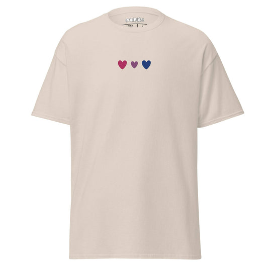 The beige Bisexual Love T-Shirt from Pridelity's Pride Collection features three small heart symbols across the chest: one red, one pink, and one dark blue.
