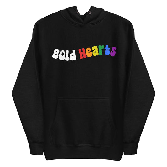 The Bold Hearts Hoodie from Pridelity is a black garment showcasing the words "Bold Hearts" on the front in a playful, wavy font to celebrate Pride. "Bold" stands out in white, while "Hearts" captivates with a vibrant rainbow gradient. This stylish piece of Pride merchandise includes a front pocket and drawstring hood for extra comfort.