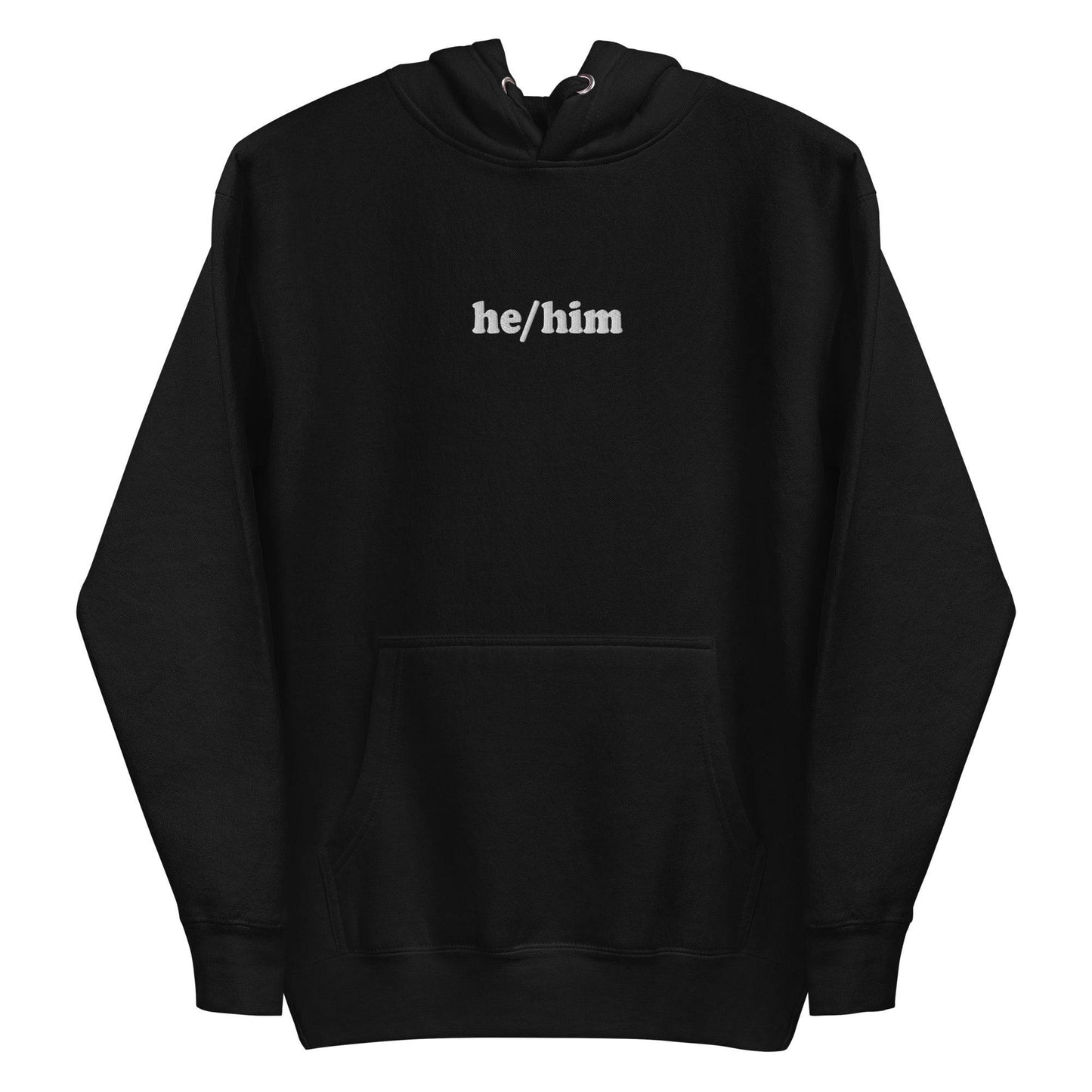 A neatly folded Pridelity He/Him Hoodie in black, featuring the text "he/him" embroidered in white on the front. The hood is showcased with its drawstrings arranged against a plain white background.