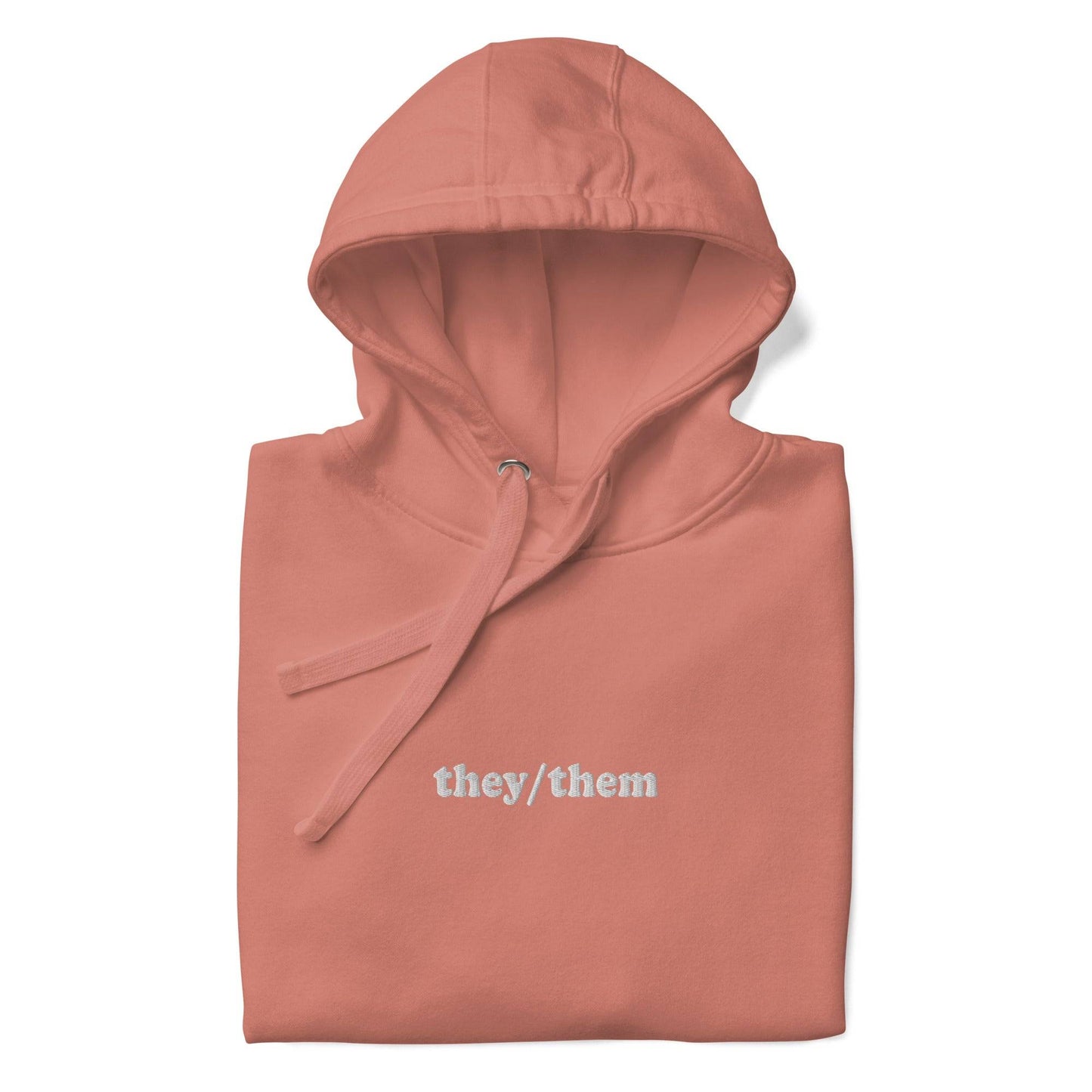 Introducing the They/Them Hoodie from Pridelity's pride collection. This LGBTQ+ friendly piece comes in a folded dusty rose color and features "they/them" text in white on the front. Complete with a drawstring, it offers a soft, casual appearance.