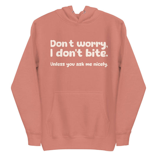 Introducing the Pridelity "I Don't Bite" Hoodie in pink, featuring bold white text on the front that reads, "Don't worry, I don't bite. Unless you ask me nicely." Perfect for those who embrace humor and identity with style.