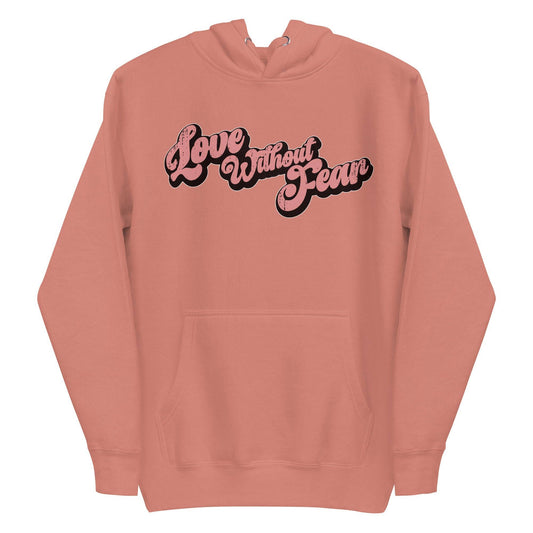 The Love Without Fear Hoodie by Pridelity comes in a dusty rose hue, featuring the phrase "Love Without Fear" across the front in a stylized, bold script reminiscent of classic pride shirts. The vintage text has contrasting black outlines and is centered on the chest. This hoodie also includes a front pocket and drawstrings.