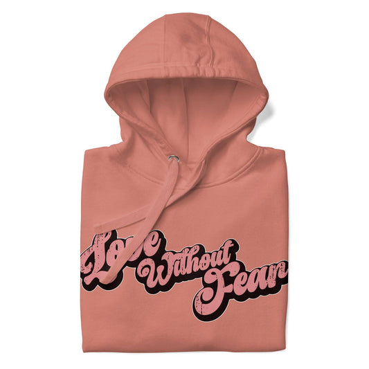 The Love Without Fear Hoodie by Pridelity comes in a dusty rose hue, featuring the phrase "Love Without Fear" across the front in a stylized, bold script reminiscent of classic pride shirts. The vintage text has contrasting black outlines and is centered on the chest. This hoodie also includes a front pocket and drawstrings.
