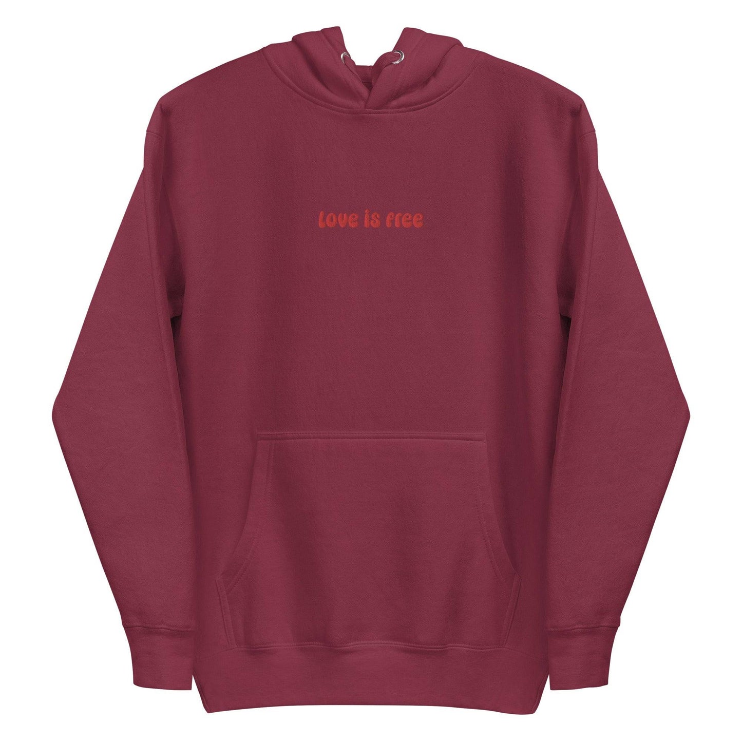 The Love Is Free Hoodie by Pridelity captures the essence of pride shirts with its folded design, featuring a hood and drawstrings, and proudly showcases the message "love is free" in red on its white front.