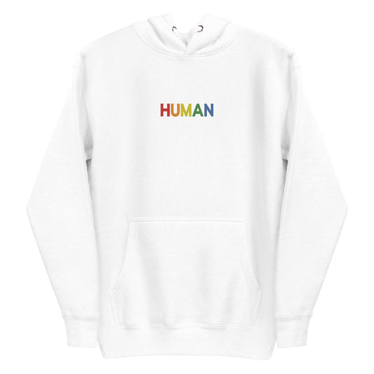 A folded Pridelity Human Hoodie, showcasing a crisp white design with "HUMAN" embroidered in vibrant rainbow colors on the front. The hood is laid flat, with its drawstrings visible, celebrating individuality and self-expression.
