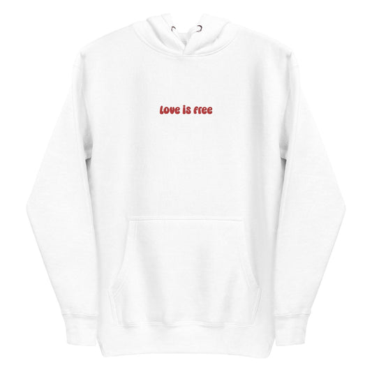 The Love Is Free Hoodie by Pridelity captures the essence of pride shirts with its folded design, featuring a hood and drawstrings, and proudly showcases the message "love is free" in red on its white front.