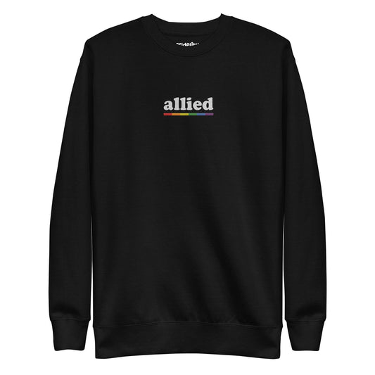 This Allied Sweatshirt by Pridelity, from our Pride Collection, showcases the word "allied" in lowercase letters. Beneath it is a multi-colored horizontal line in shades of gray, blue, yellow, black, and red to honor diversity. The look is finished with a classic crew neck for timeless style.