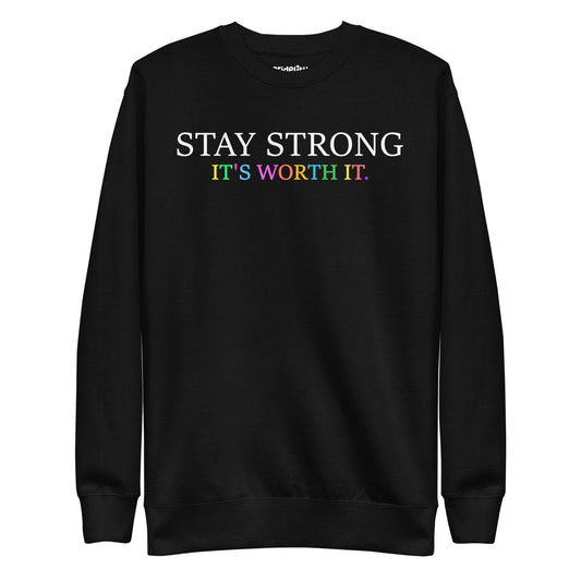 Introducing the "Stay Strong Sweatshirt" by Pridelity from their pride collection. This black sweatshirt features the powerful message "STAY STRONG IT'S WORTH IT." The words "STAY STRONG" stand out in bold white, while "IT'S WORTH IT." radiates in vibrant rainbow colors, making it an ideal choice for celebrating pride.
