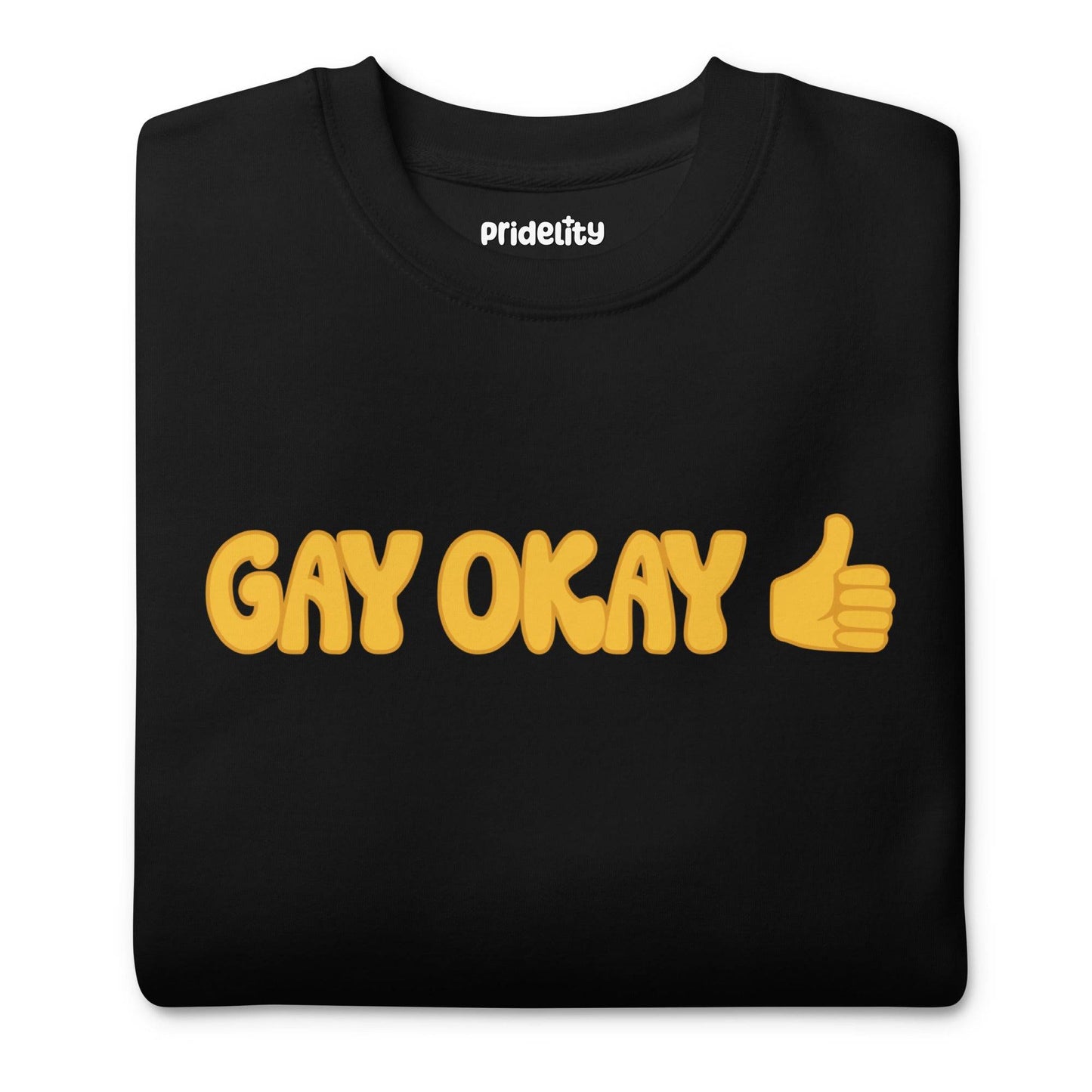 The Pridelity Gay Okay Sweatshirt is a black top adorned with the words "GAY OKAY" in bold yellow lettering and a thumbs-up emoji, offering a stylish way to celebrate pride with its rainbow-themed design.
