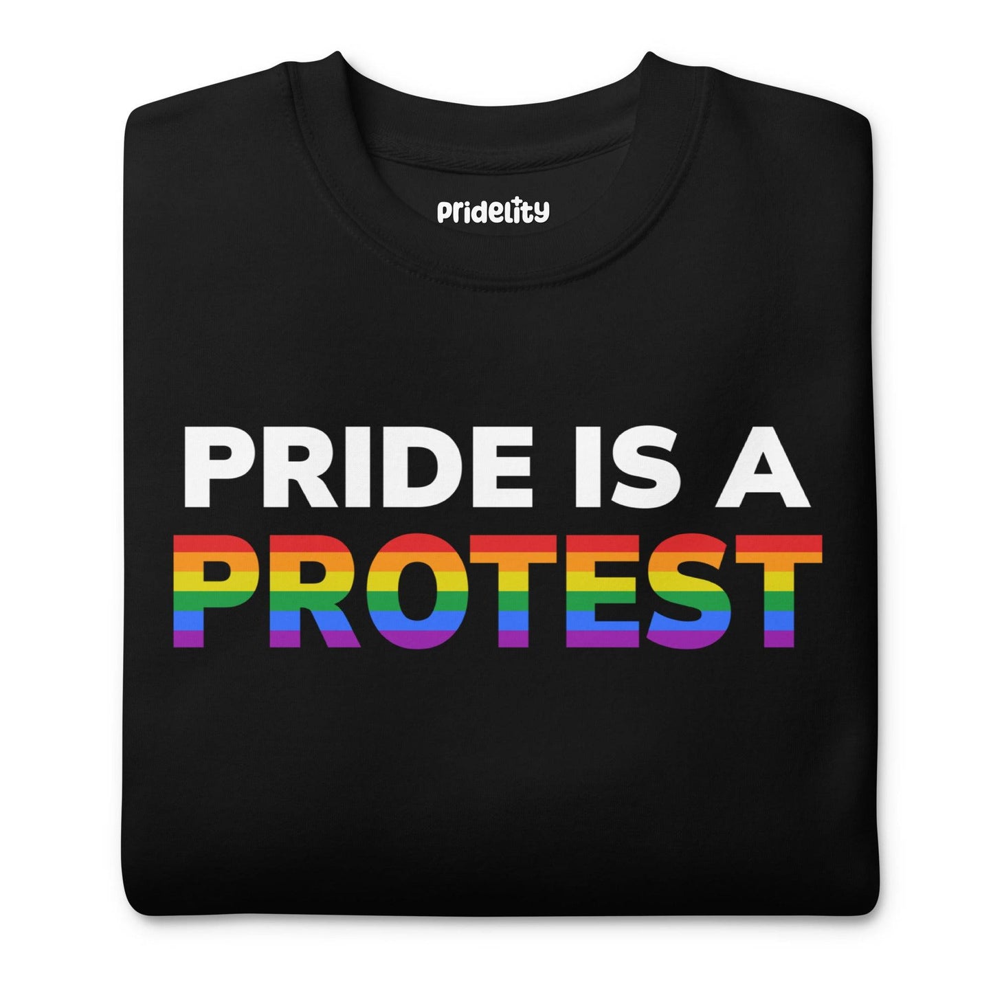 Introducing the "Pride is a Protest" Sweatshirt by Pridelity. This black sweatshirt prominently displays the message "Pride is a Protest," with the word "Protest" shining in vibrant rainbow colors, capturing the essence of the LGBTQ+ pride flag. It’s an ideal choice for any pride outfit and a highlight of our pride collection.