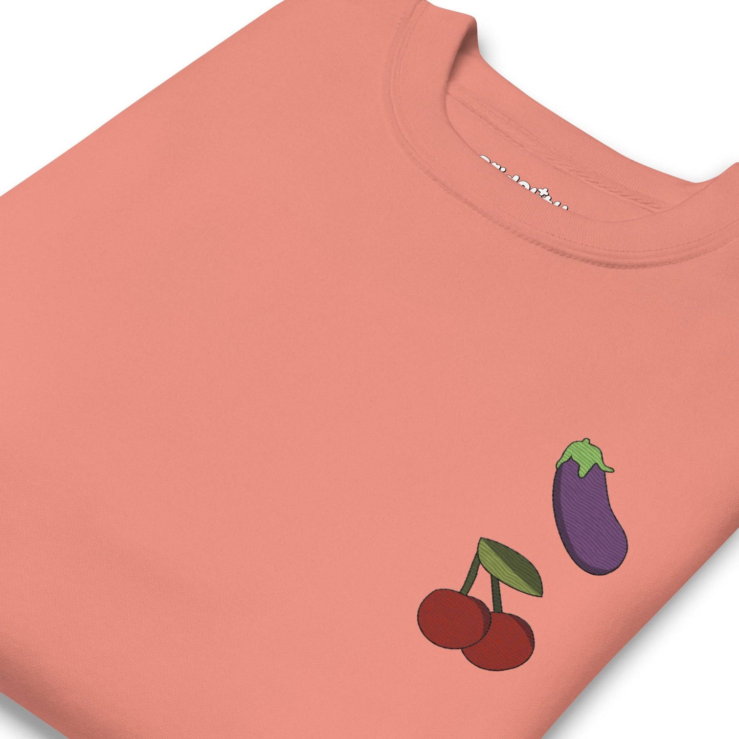 Check out the "Yummy Emojis Sweatshirt" by Pridelity in a dusty rose hue, showcasing small embroidered designs of an eggplant and cherries on the upper left side. This sweatshirt, from our exclusive pride collection, features a classic crew neck and long sleeves, making it perfect for any pride ensemble.