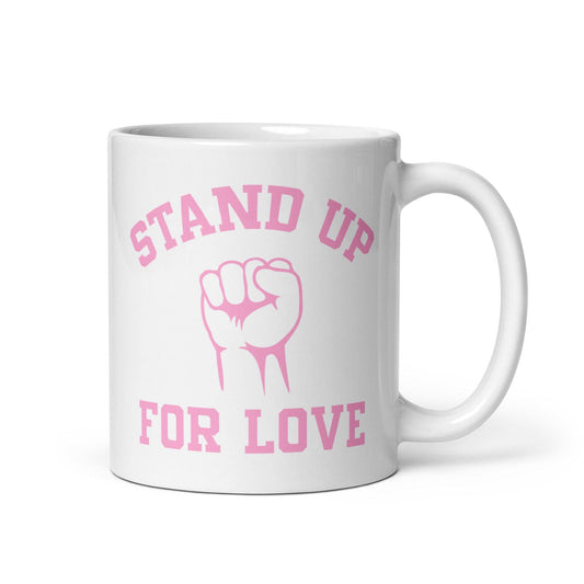 The "Stand Up For Love" mug from Pridelity features pink text on a white background, reading "Stand Up for Love," with an image of a raised fist between the words. As part of the Pride Collections 2025, it symbolizes unity and love.