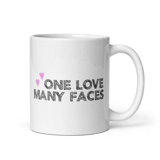 The One Love Many Faces Mug by Pridelity, part of the Pride Collections 2025, showcases the phrase "One Love Many Faces" in bold black letters. It is adorned with two small pink hearts on the left side above the text, all set against a plain white background to celebrate unity and diversity.