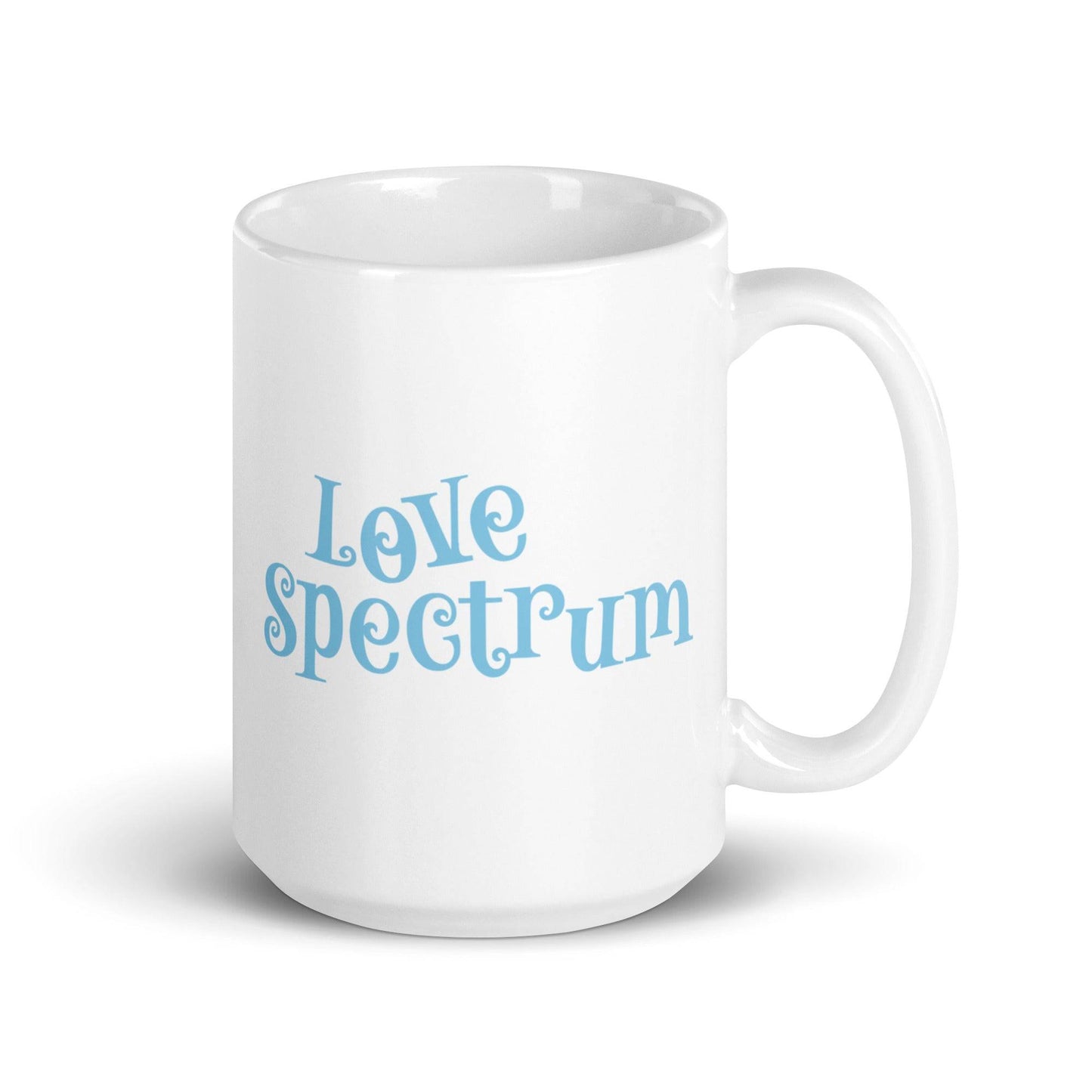 A white coffee mug featuring "Love Spectrum" in light blue, playful letters on one side is part of Pridelity's pride collection for 2025 and showcases a simple and clean design.