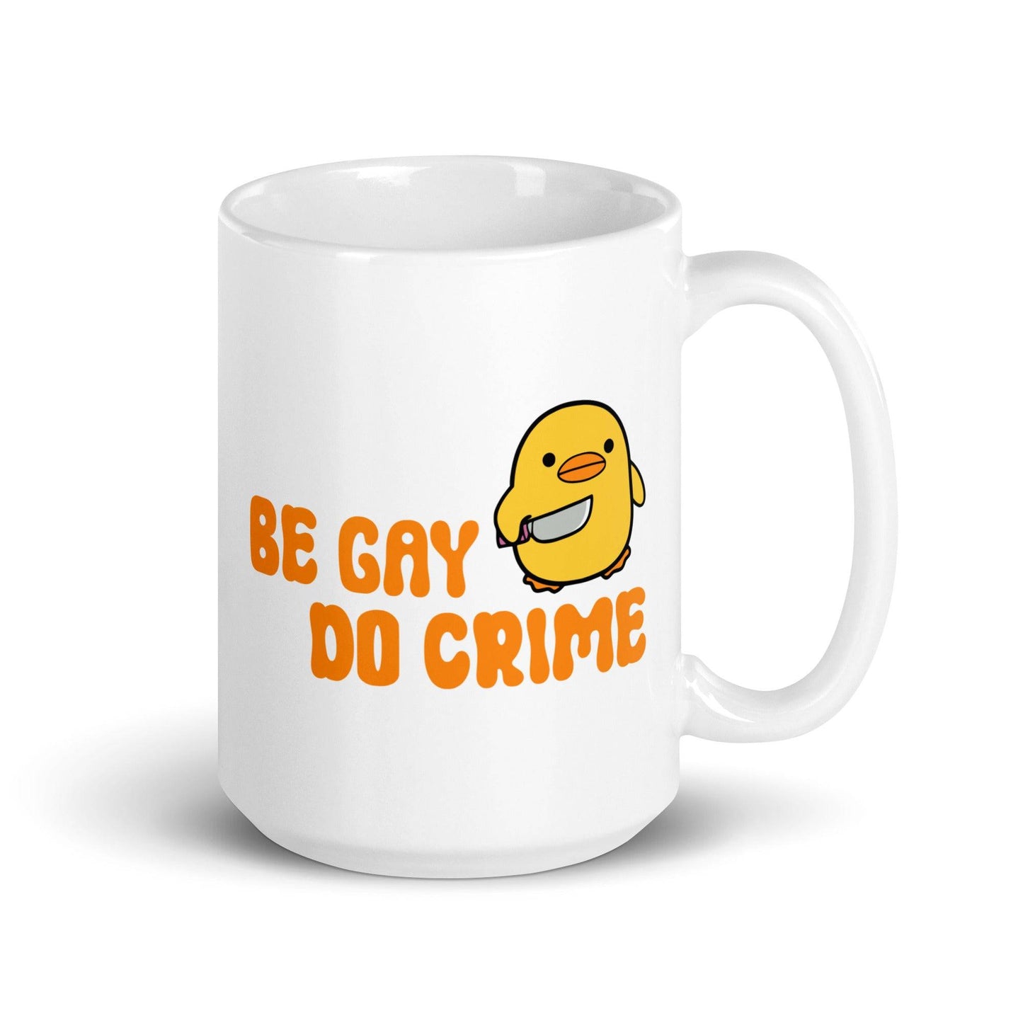 This white mug from Pridelity's Be Gay Do Crime collection showcases a cute yellow duck holding a knife, accompanied by bold orange text reading "Be Gay Do Crime.