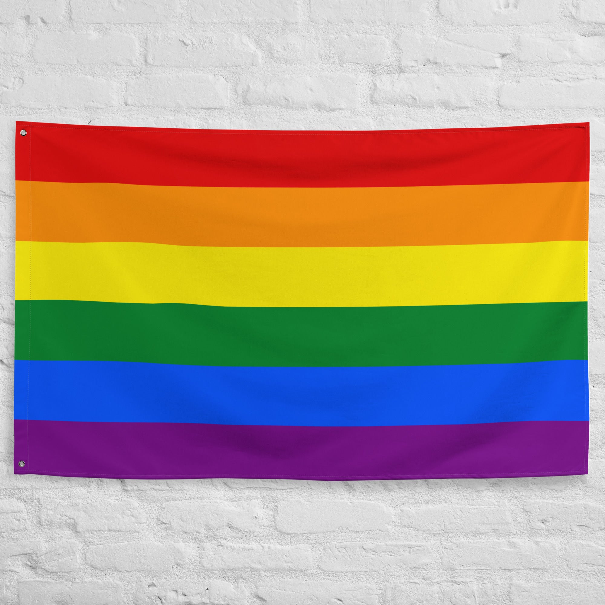 A Traditional Pride Flag from Pridelity, featuring six horizontal stripes in red, orange, yellow, green, blue, and purple, adorns the white brick wall of a charming rainbow shop.