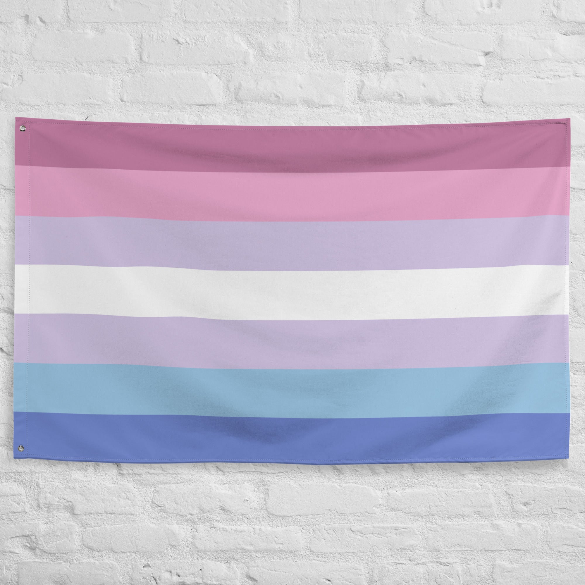 A Pridelity Bigender Pride Flag, featuring horizontal stripes in shades of pink, white, and blue, hangs proudly against a white brick wall.