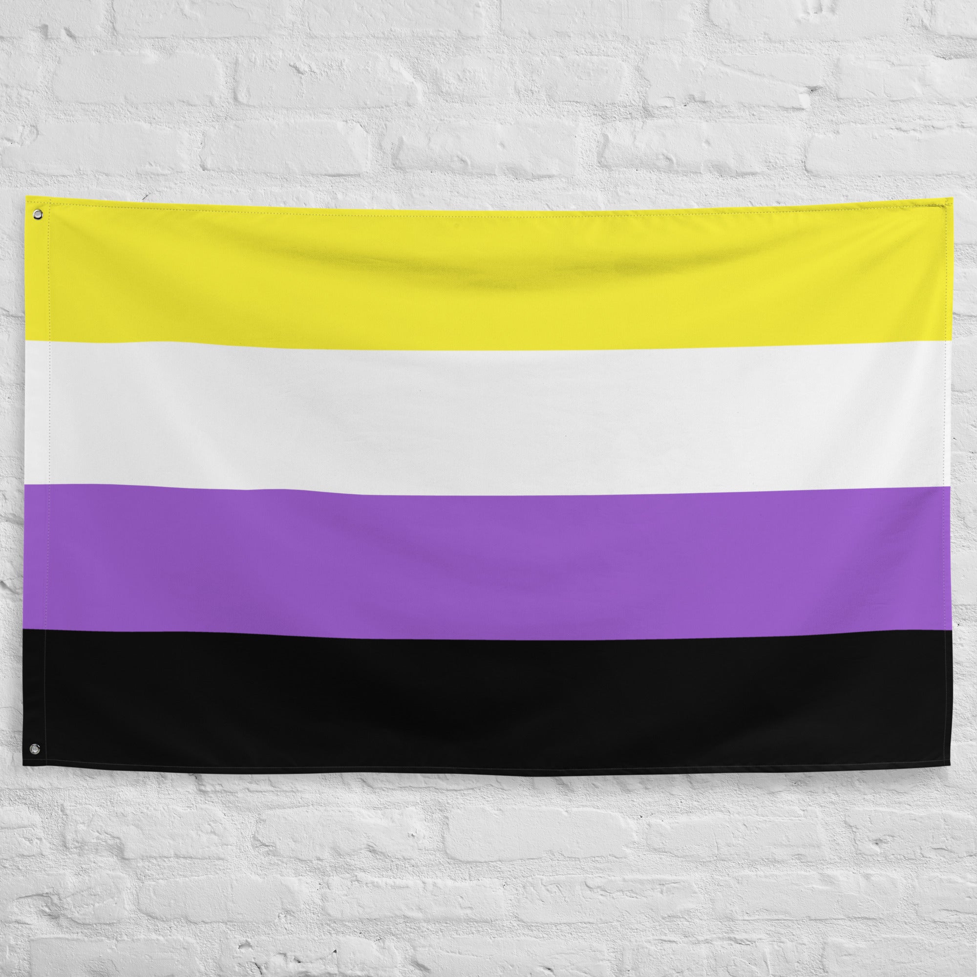 A vibrant Nonbinary Pride Flag from Pridelity, featuring horizontal stripes in yellow, white, purple, and black, hangs proudly on a white brick wall at the entrance of the rainbow shop.