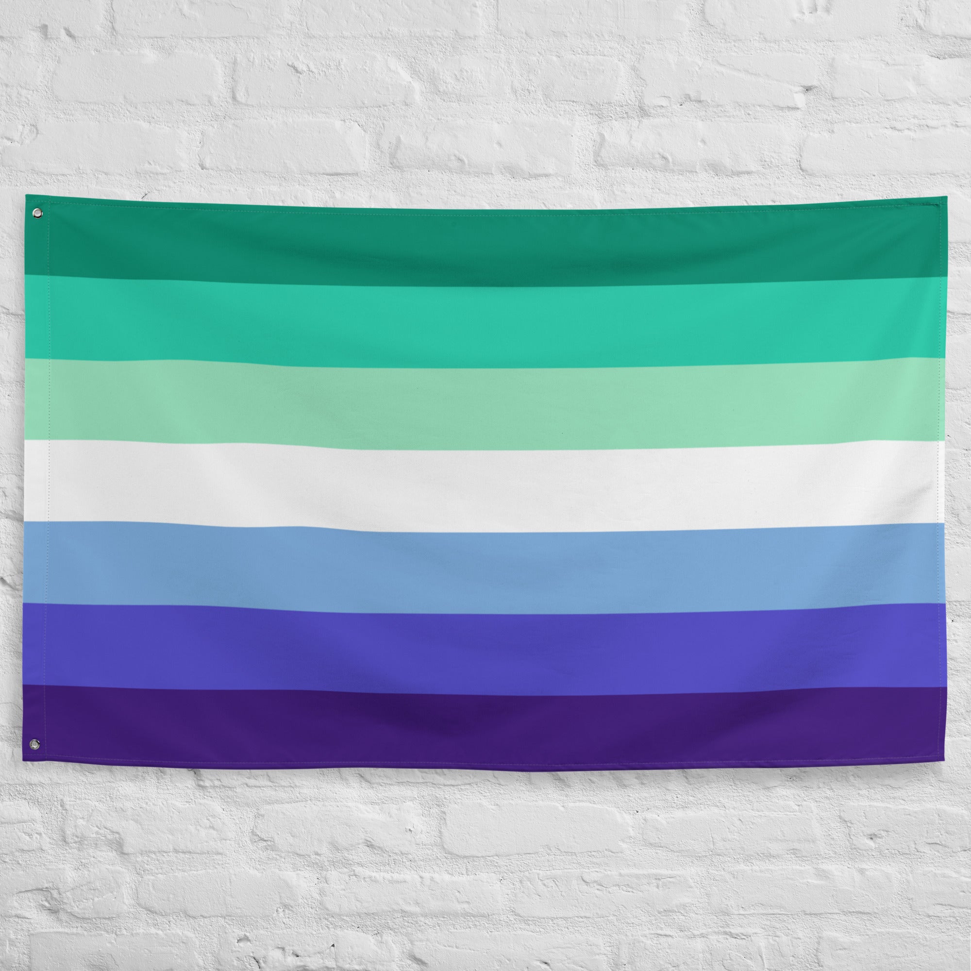 The Gay Men Pride Flag by Pridelity features horizontal stripes in a spectrum of colors reminiscent of a vibrant rainbow shop display. The flag showcases green, aqua, white, light blue, blue, and dark blue stripes descending against a white brick wall background.