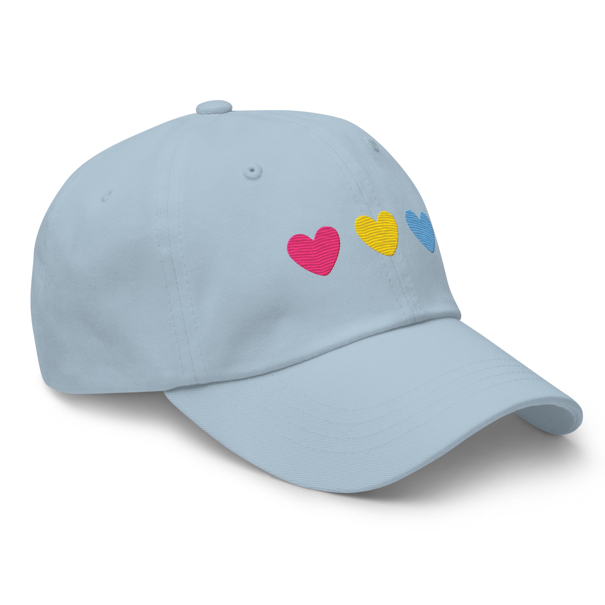 The Pan Hearts Cap by Pridelity, in a light blue hue, brings a playful touch to pride outfits with its three vibrantly embroidered hearts in pink, yellow, and blue.