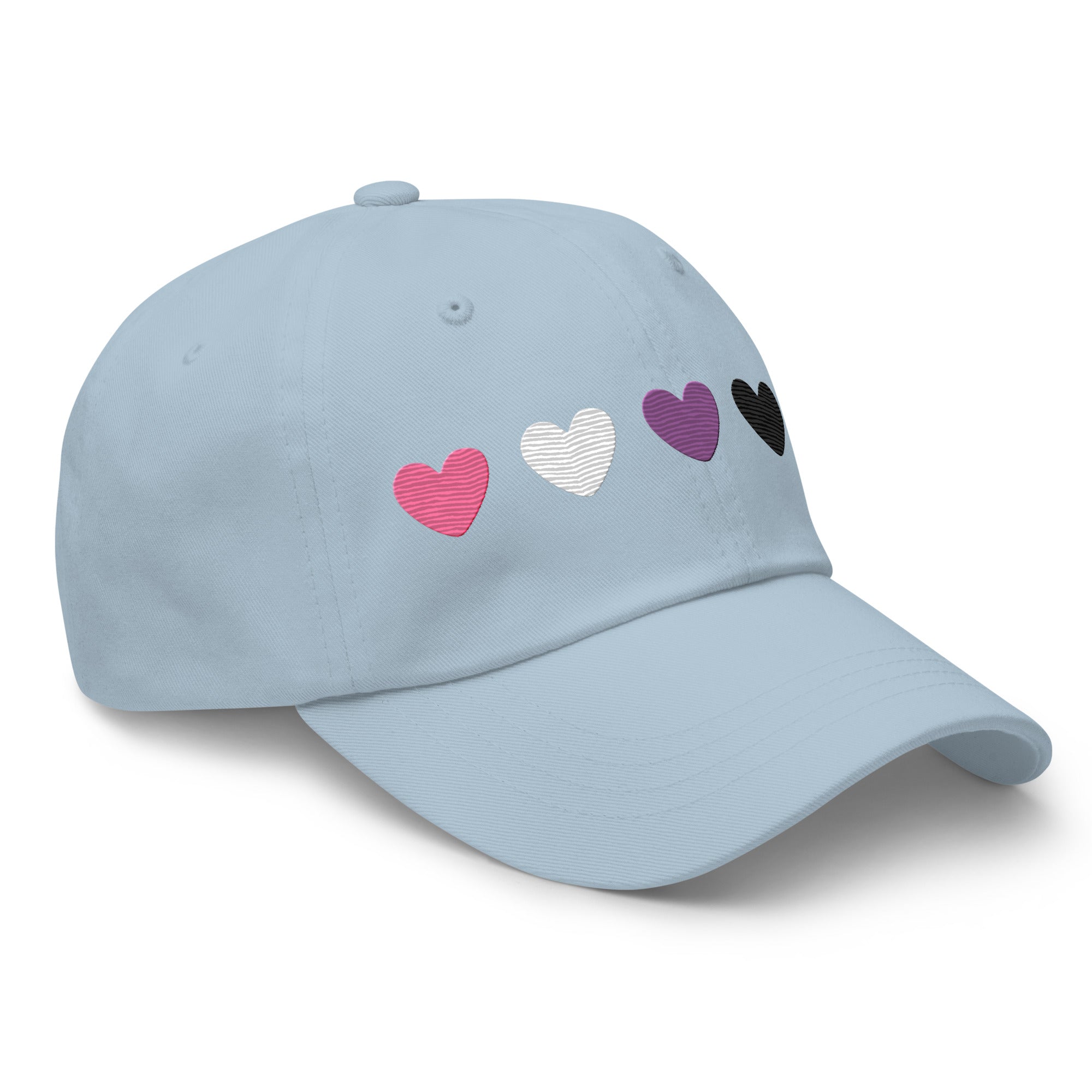 Introducing the Genderfluid Hearts Cap by Pridelity—a light blue baseball cap featuring five embroidered hearts in a vibrant spectrum of pink, gray, white, purple, black, and blue that captures the essence of pride outfits.