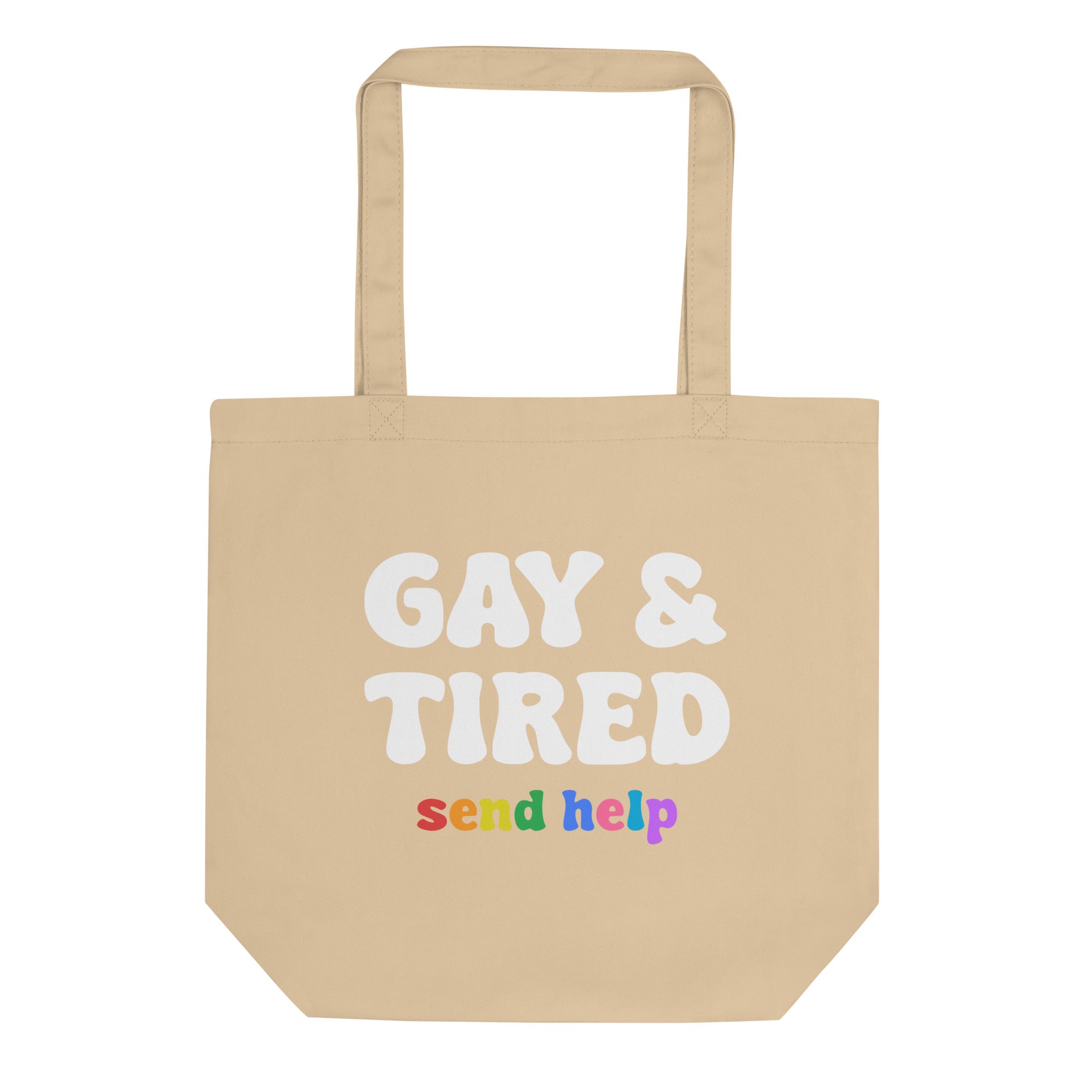 A black tote bag from Pridelity, known as the Gay & Tired Tote Bag, prominently displays 